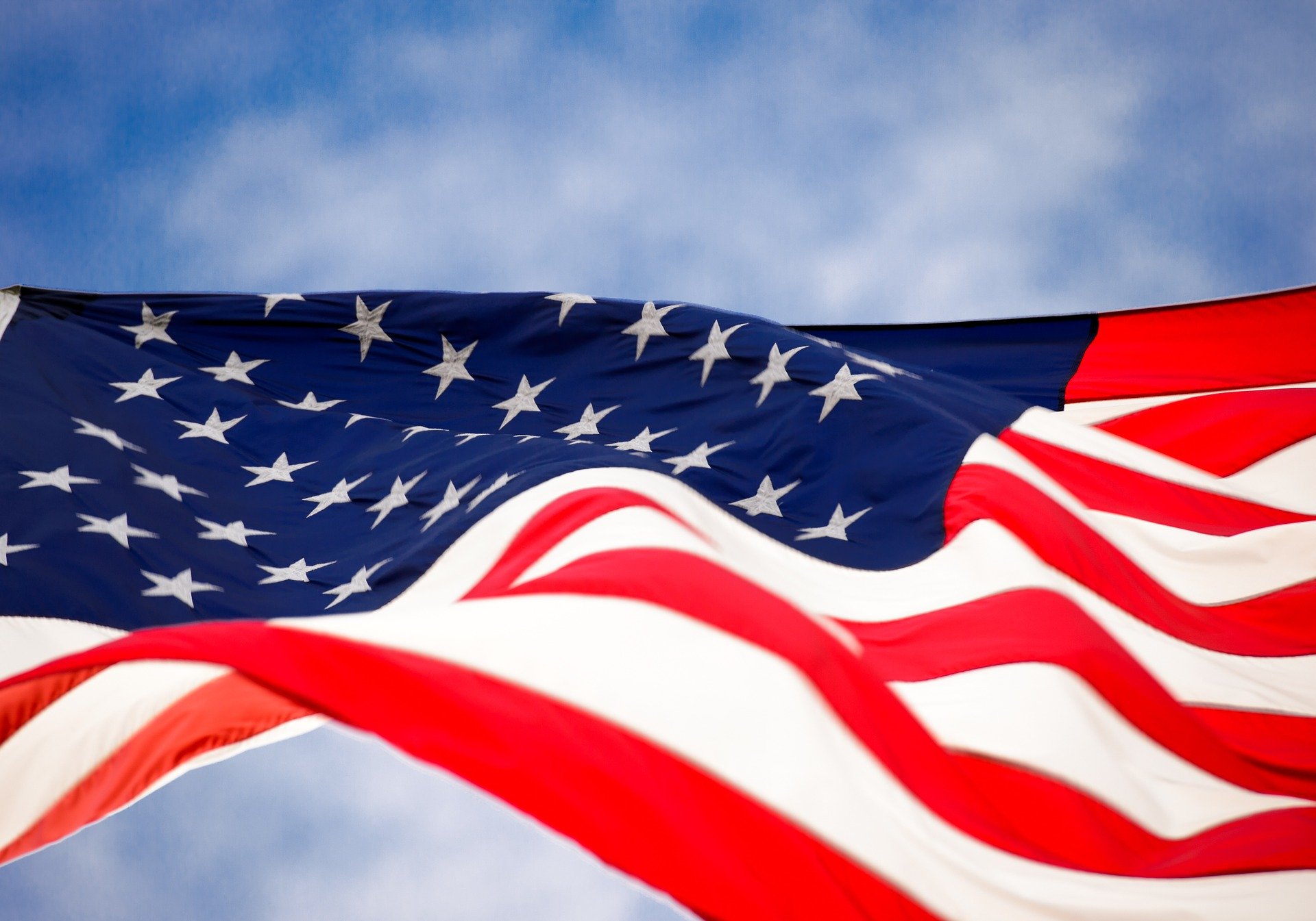 Waving American flag against a bright blue sky.