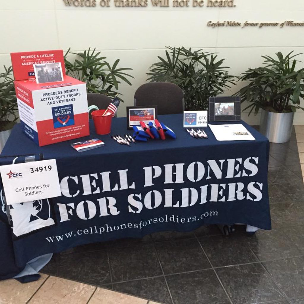 Cell Phones For Soldiers volunteer table with donation materials and promotional items.